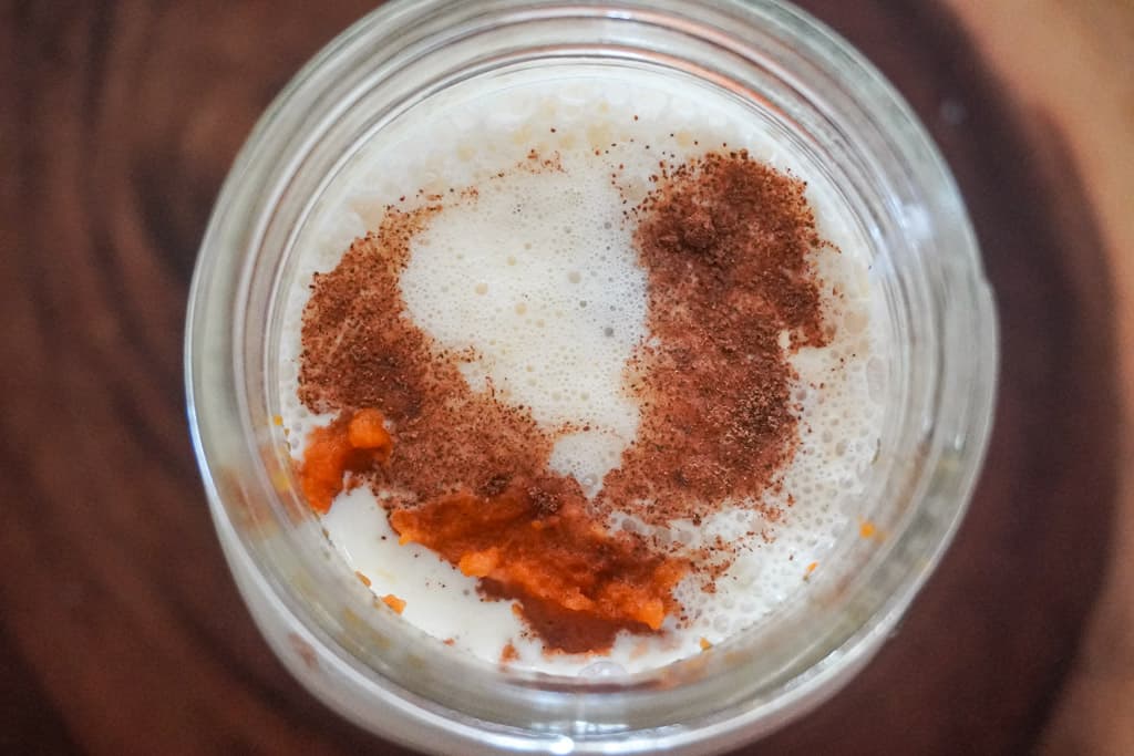 overhead view of a mason jar filled with ingredients for pumpkin cold foam