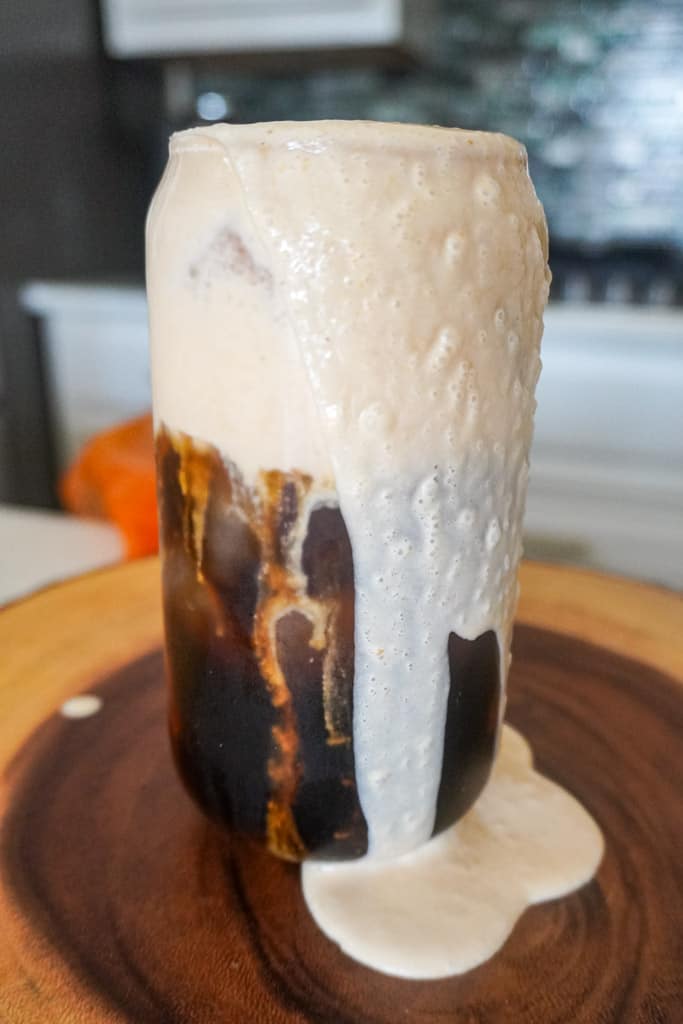 a glass of pumpkin cream cold brew overflowing with cold foam