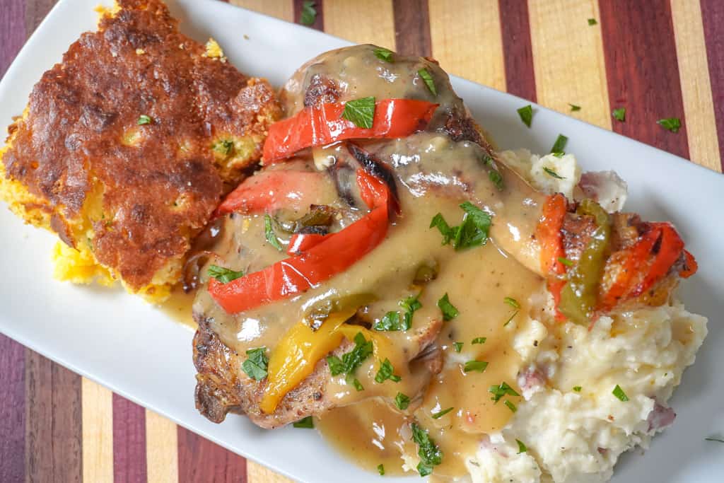 plated smothered chicken with veggies, mashed potatoes, and cornbread