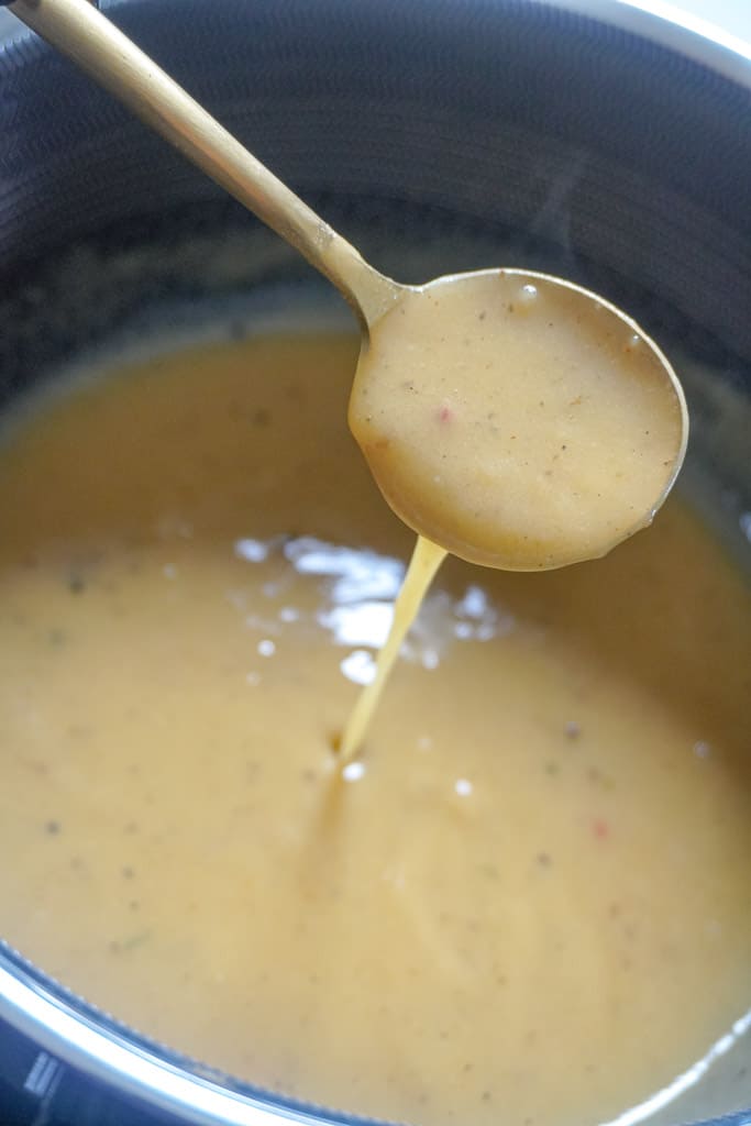 chicken gravy in a pot with a spoon hovering over it