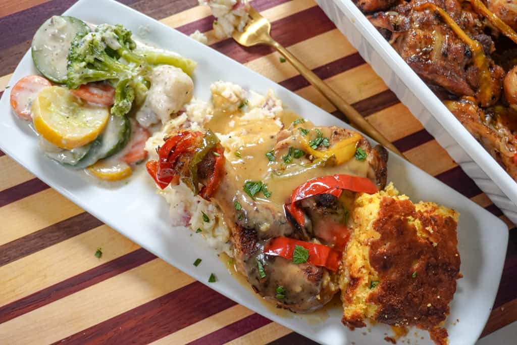 plated smothered chicken with veggies, mashed potatoes, and cornbread