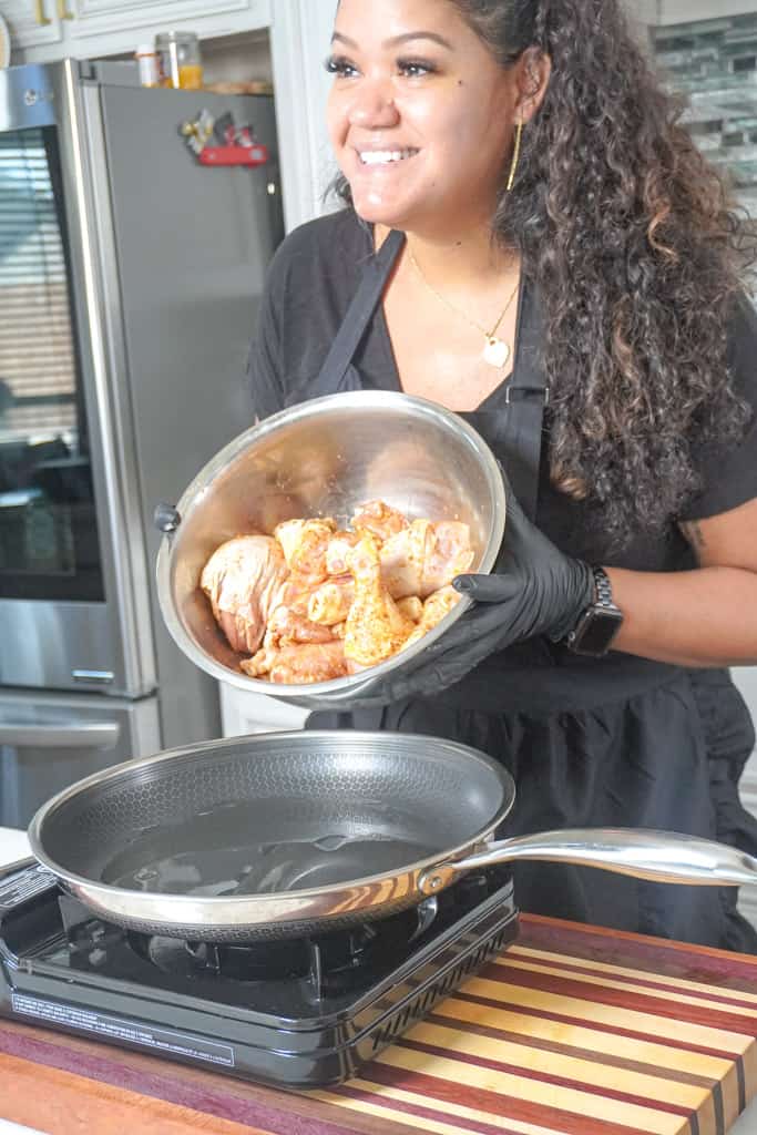 Tamara putting seasoned chicken into a skillet