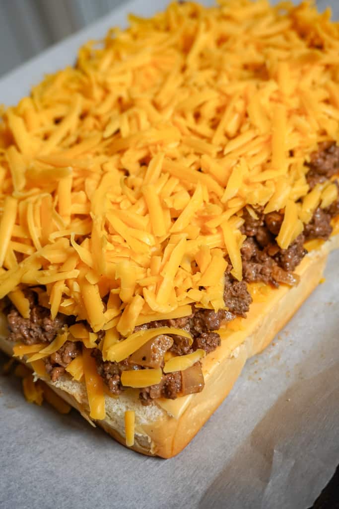 shredded cheese over ground beef mixture on hawaiian rolls