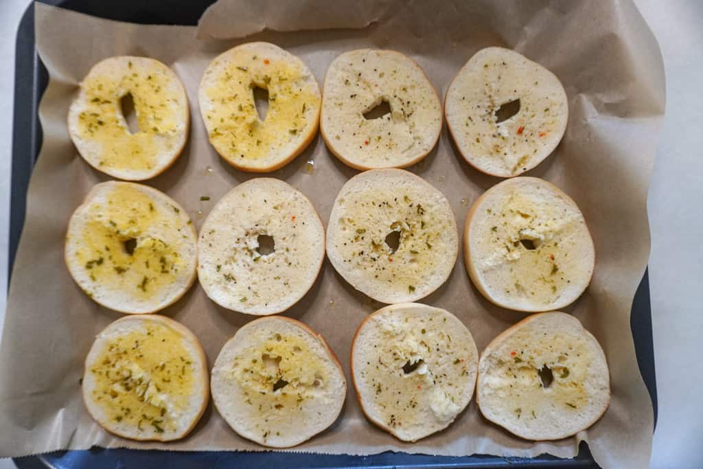 buttered and lightly toasted bagels on parchment lined air fryer tray