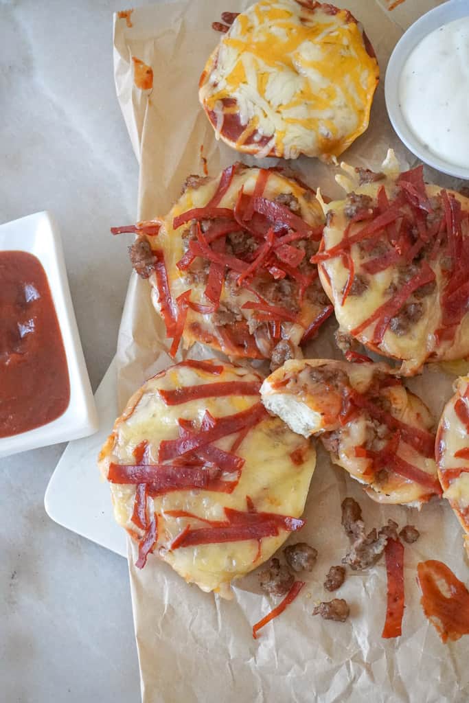 air fryer bagel bites on parchment paper alongside dipping sauces