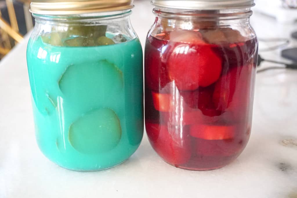strawberry and blue raspberry kool aid pickles in a jars on the counter
