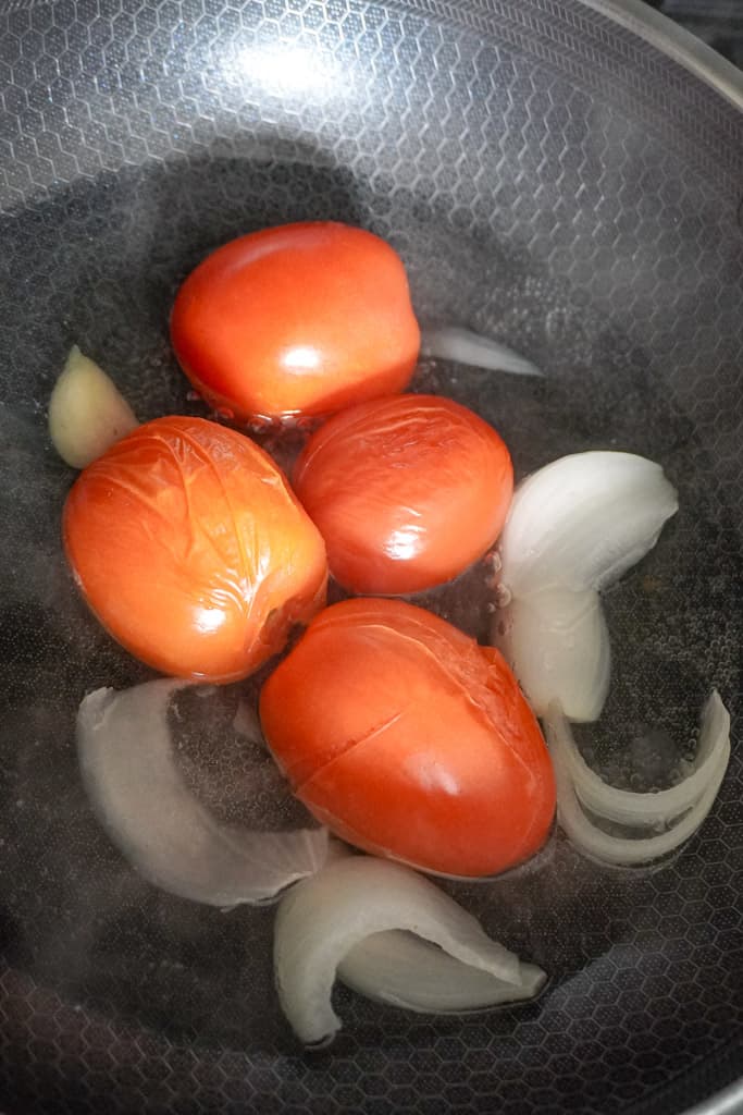tomatoes, onions, and garlic boiling in a pot