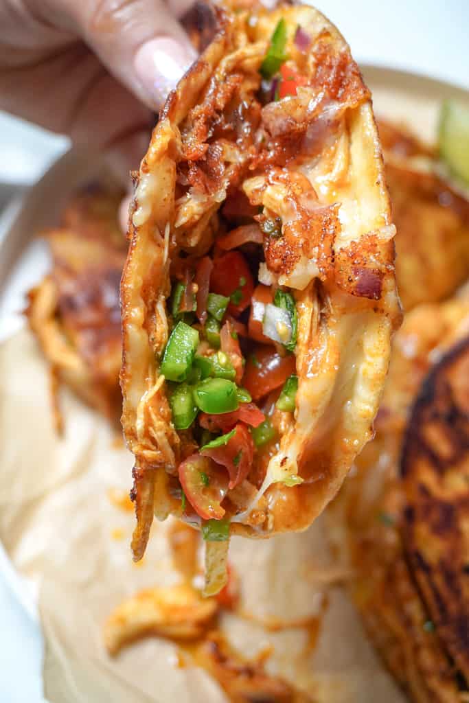close up view of a hand holding a chicken tinga taco