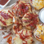 air fryer bagel bites on parchment paper alongside dipping sauces