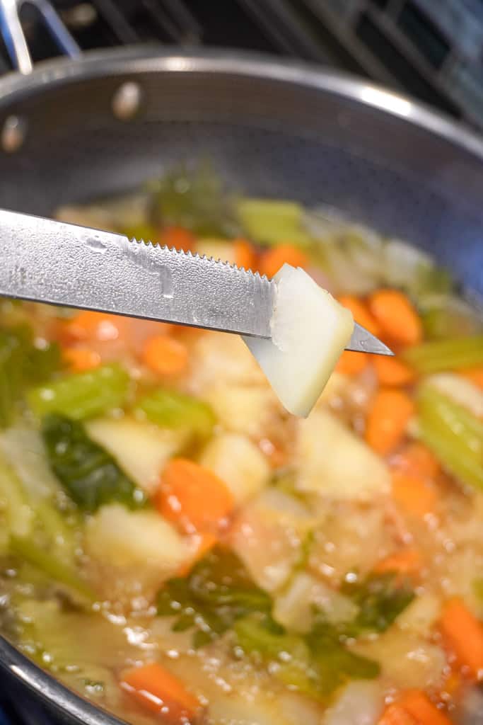 a knife inserted into a diced potato to show its fork tender