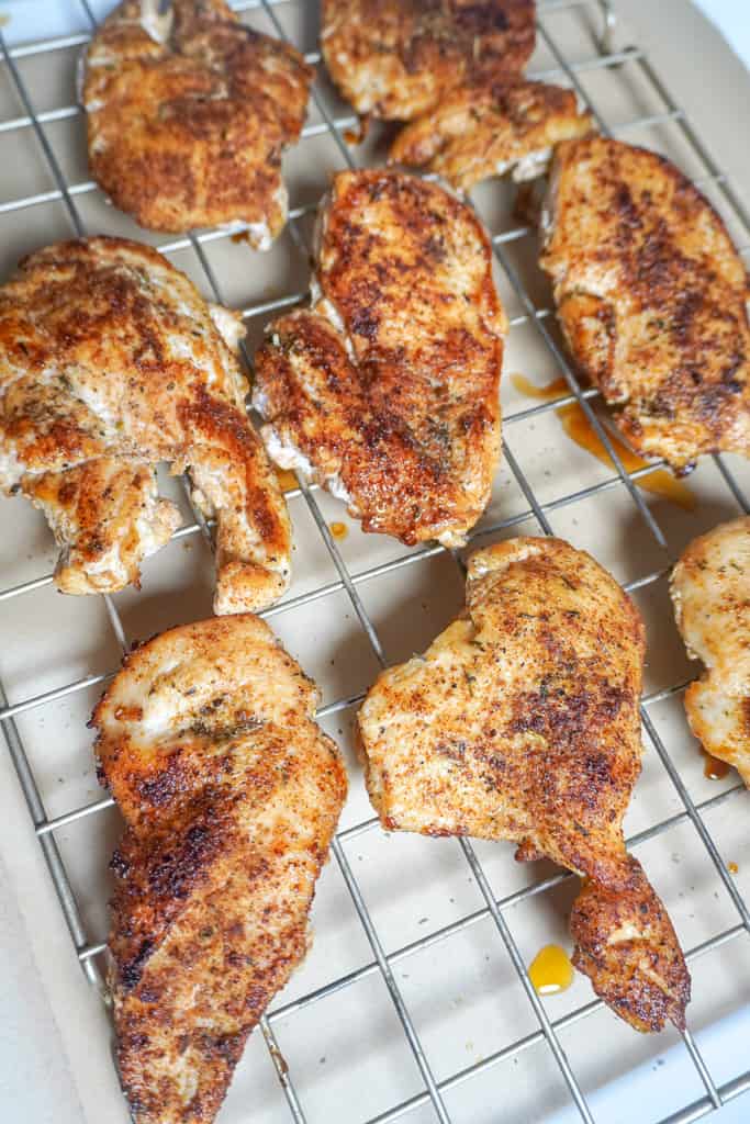cooked chicken breasts on a cooling rack