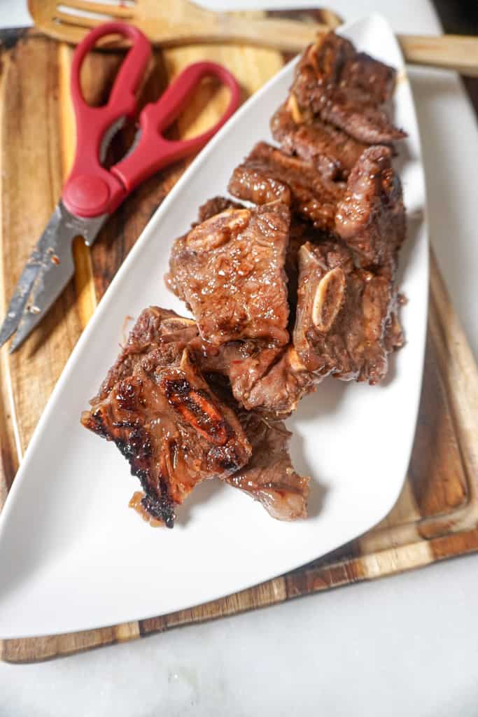 flanken short ribs on a plate beside a pair of scissors