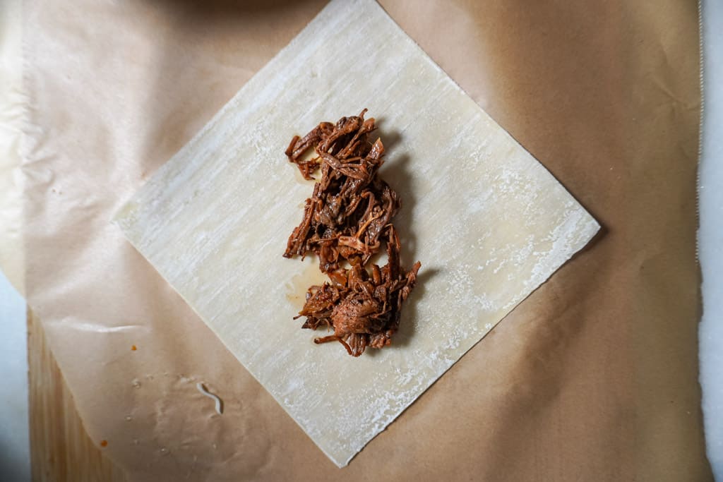 birria placed in the center of an unwrapped egg roll wrapper