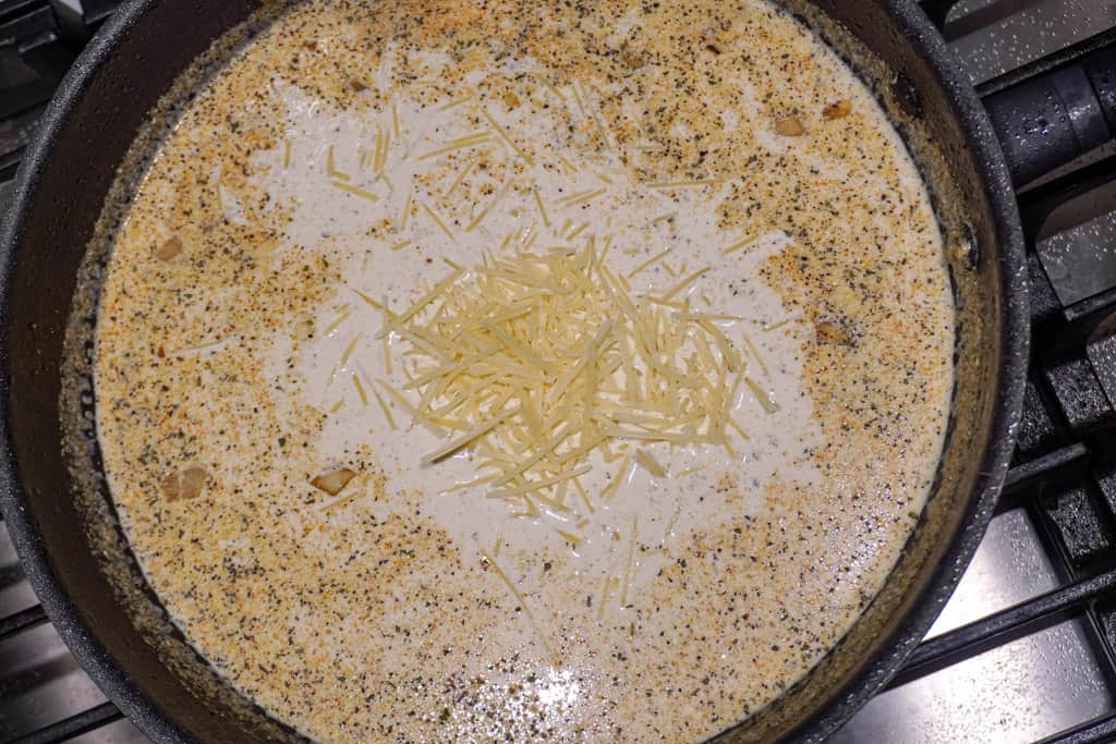shredded cheese added to milk based mixture in a skillet