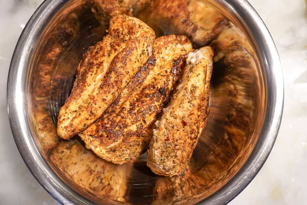 recipe for Chicken alfredo lasagna overhead view of a bowl of cooked, seasoned chicken