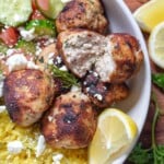 close up view of greek chicken meatballs in a yellow rice bowl