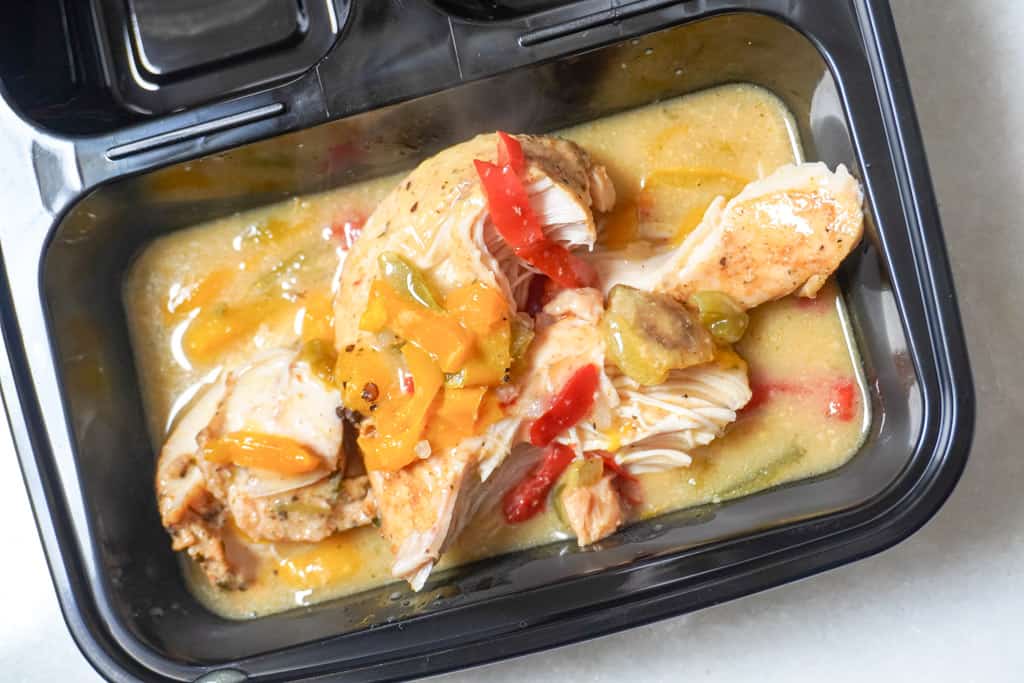 a single serving of smothered chicken breast in a black takeout container