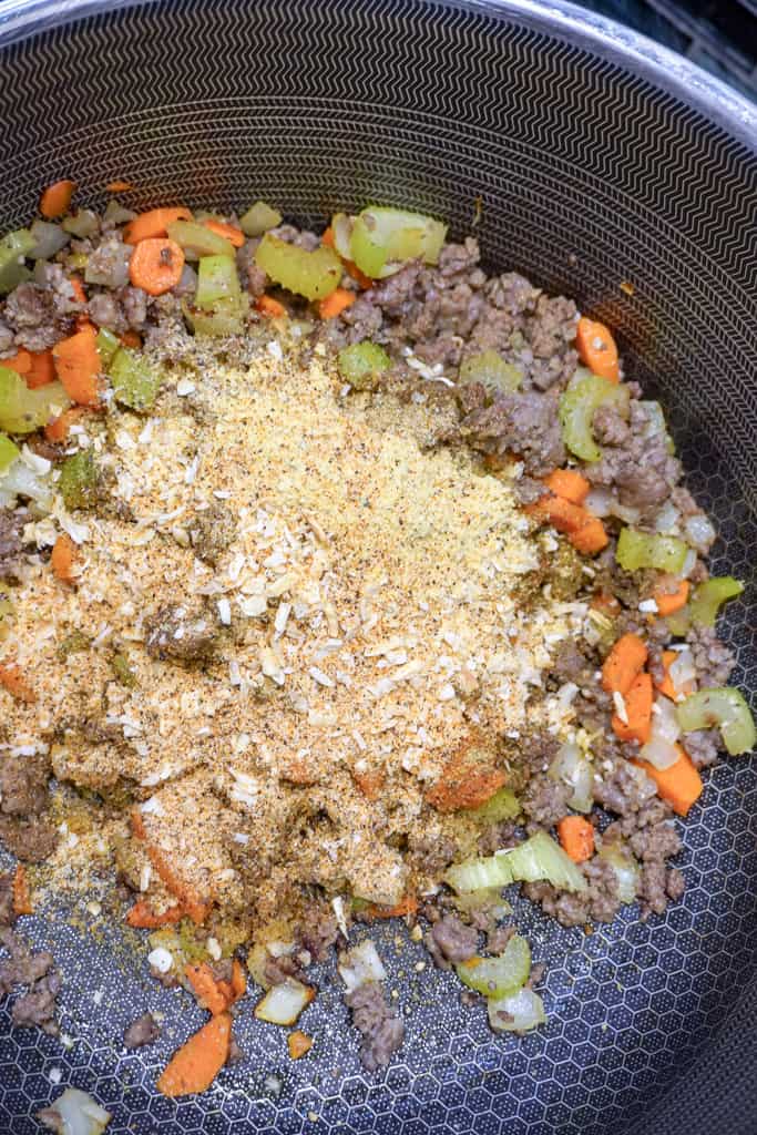 chopped veggies and seasoning added to large pot with cooked ground sausage