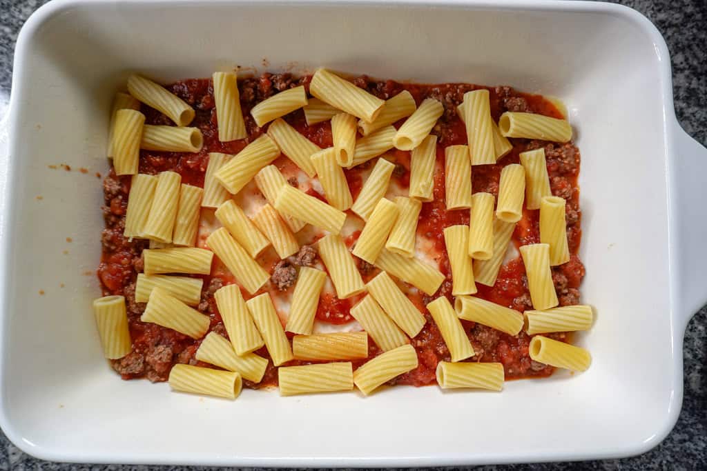 the first layer of rigatoni pasta in a dish