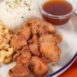 plated Sweet Hawaiian Crockpot Chicken with a small saucer of sauce, macaroni salad, and rice