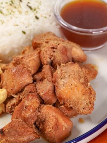 plated Sweet Hawaiian Crockpot Chicken with a small saucer of sauce, macaroni salad, and rice