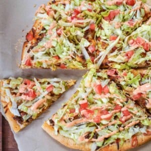 sliced taco pizza on parchment paper with one slice further away from the rest