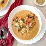 chicken taco soup in a white bowl with pico de gallo on top as garnish