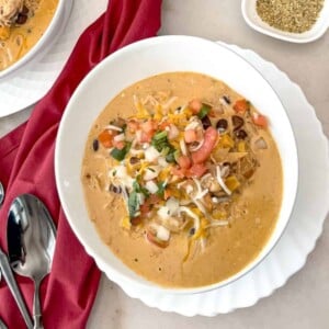 chicken taco soup in a white bowl with pico de gallo on top as garnish