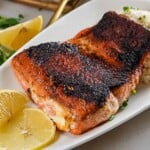 salmon on a white plate with lemon wedges