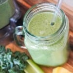 overhead view of green smoothie in a glass myg with a handle with a straw inserted