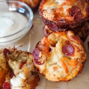 close up view of pepperoni pizza bites on parchment paper with a small saucer of ranch dipping sauce