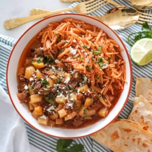 picadillo or ground beef with potatoes in a white bowl with quesadillas next to it on a table