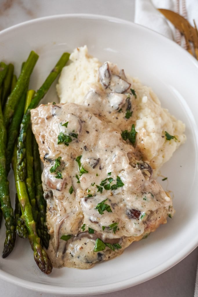 garlic parmesan chicken on a plate with mashed potatoes and asparagus