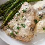 garlic parmesan chicken on a plate with mashed potatoes and asparagus