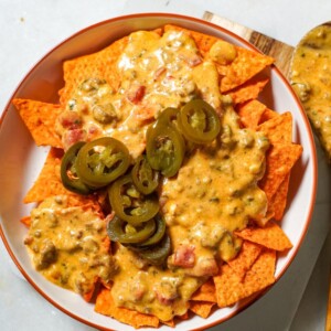 rotel dip with ground beef on a bed of doritos topped with jalapenos