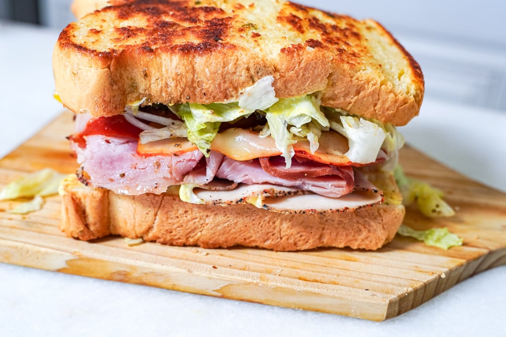 side view of a whole club sandwich on a cutting board