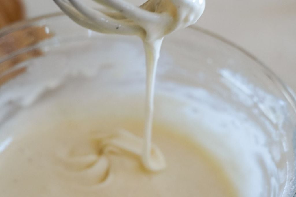 icing in a bowl with a whisk scooping it out