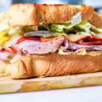 side view of a whole club sandwich on a cutting board