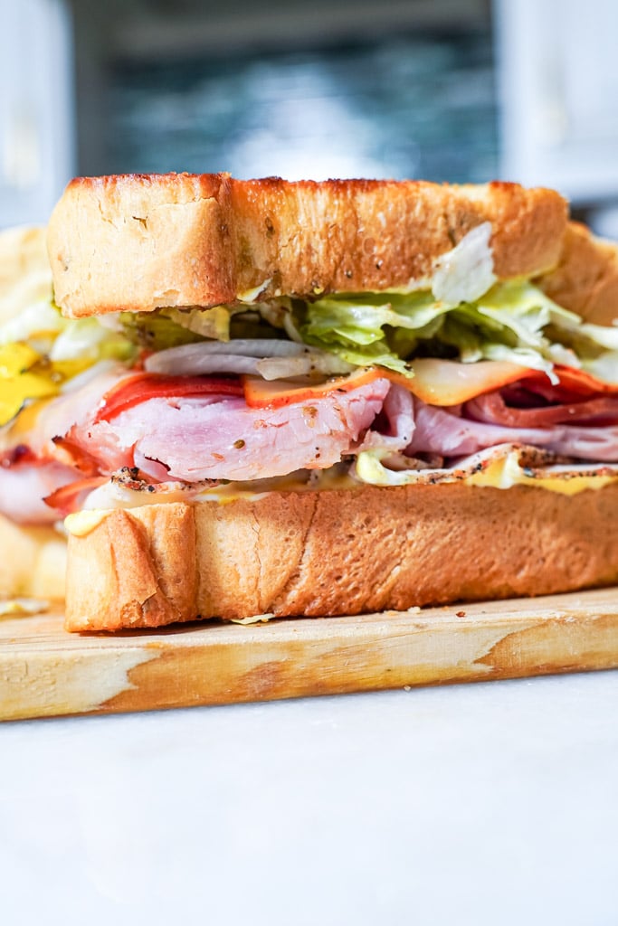 side view of a whole club sandwich on a cutting board