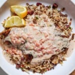 blackened catfish with a cream sauce in a bowl over a bed of dirty rice