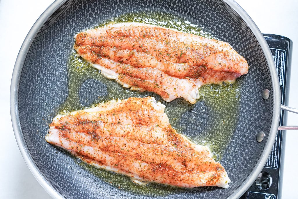 blackened catfish cooking in a skillet