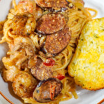 Cajun pasta plated on a white plate with a side of garlic toast