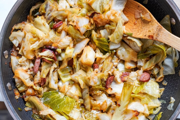 fried cabbage in a pot with a wooden spoon