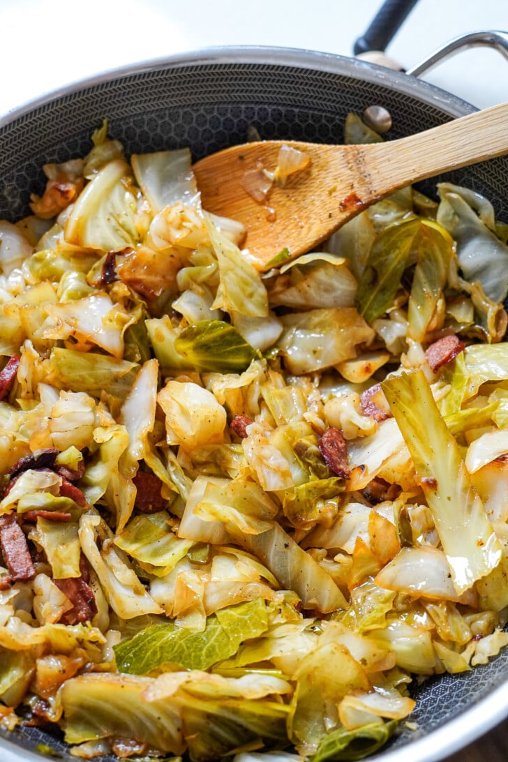 fried cabbage in a pot with a wooden spoon