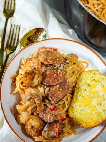 Cajun pasta plated on a white plate with a side of garlic toast