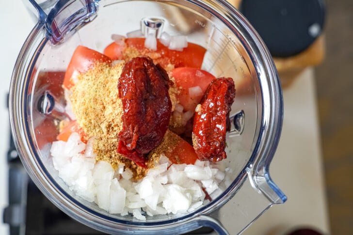 tomatoes, onions, and seasoning in a blender to make a sauce for albondigas soup