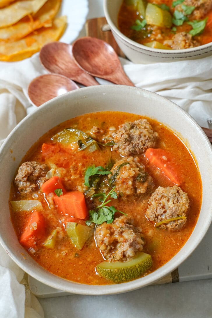 a close-up of albondigas soup in a white bowl