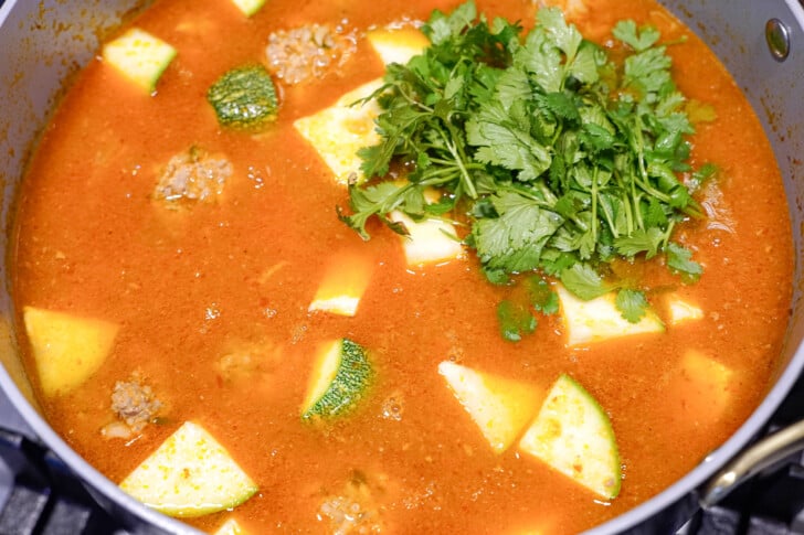 albondigas soup in a pot with chopped cilantro on to