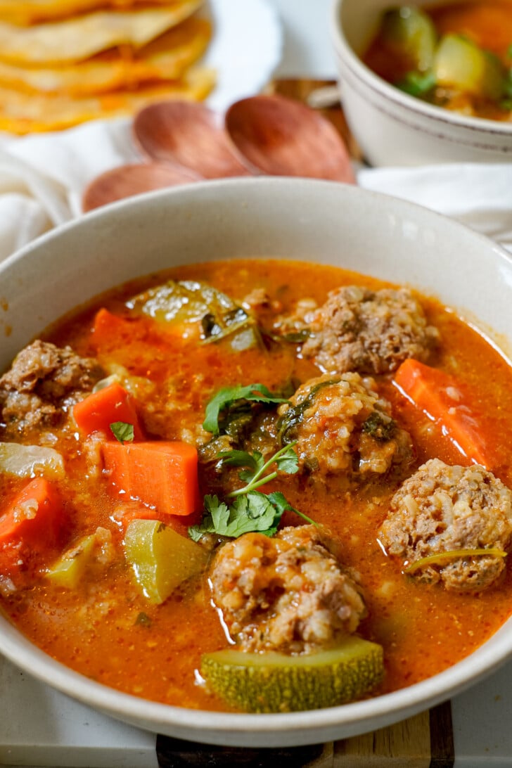 a close-up of albondigas soup in a white bowl