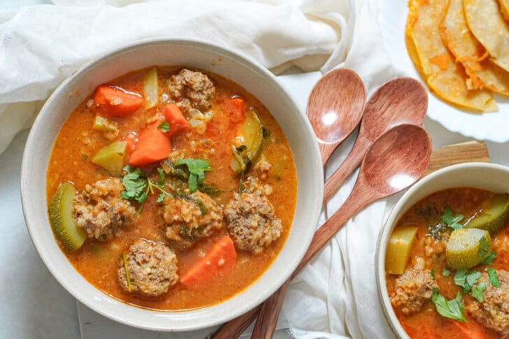 a close-up of albondigas soup in a white bowl